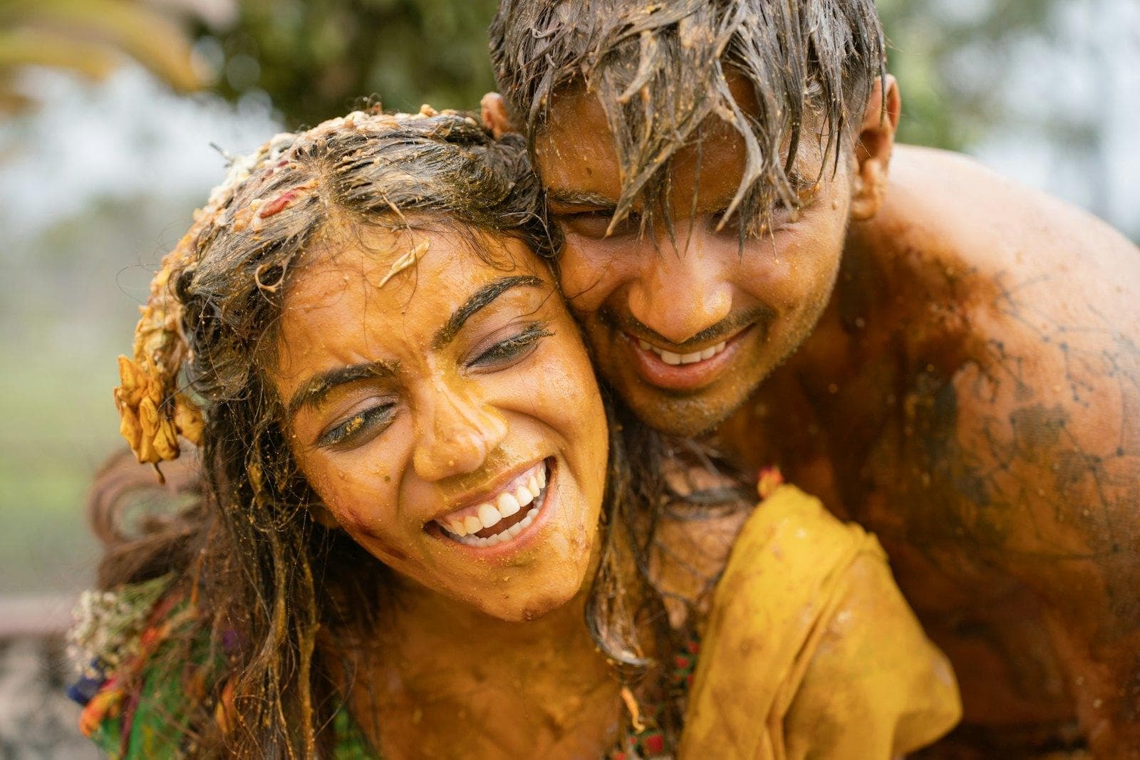 A laughing couple covered in turmeric paste at their haldi