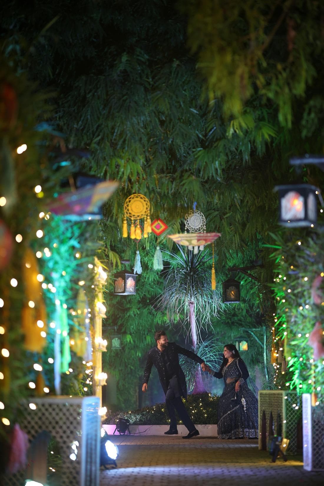A couple dancing at night in a garden strung with lights